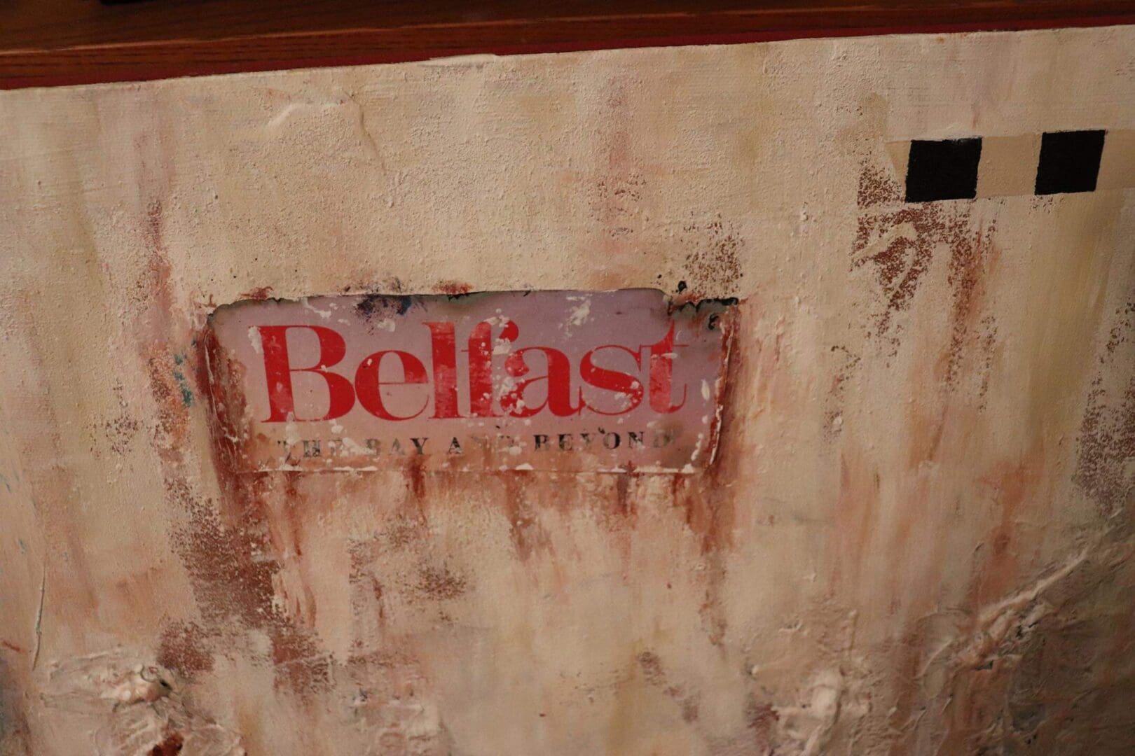 Rusty sign with faded red text reading 'Belfast'.