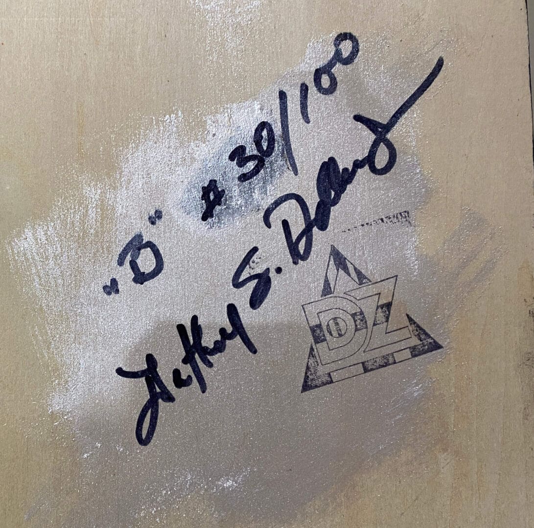Signature and date on a wooden surface with a small drawing of a building.