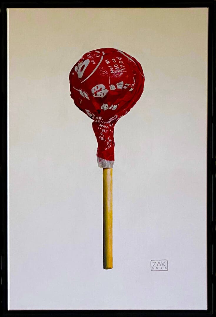 A red lollipop with white patterns on a yellow stick.