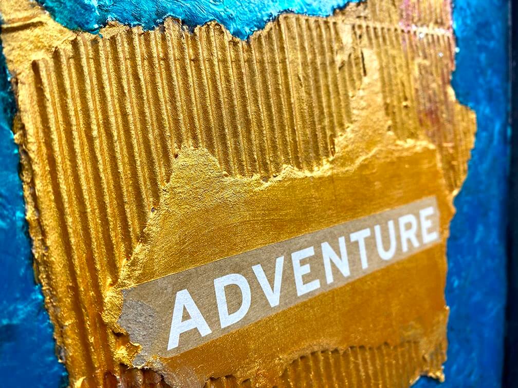 Close-up of a textured surface with the word 'ADVENTURE' on a torn paper.