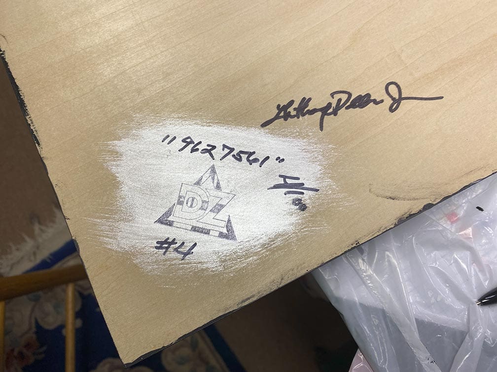 Signed wooden board with inscriptions and a triangle symbol.