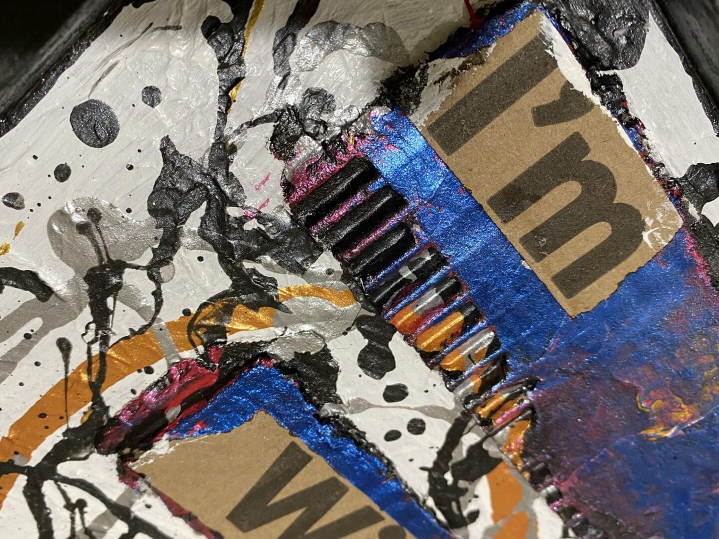 Close-up of a colorful, abstract mixed-media artwork with torn paper and paint splatters.