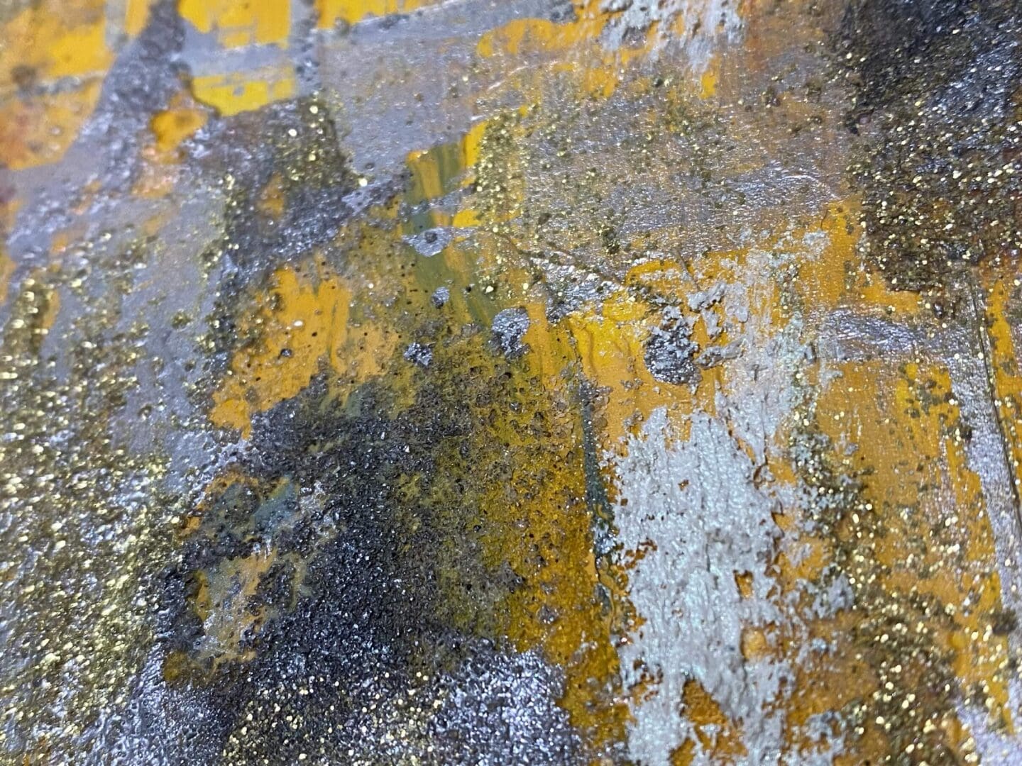 Close-up of textured surface with yellow, gray, and white paint.