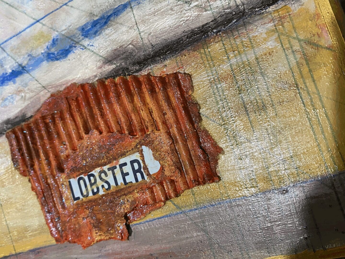 A textured, rusty metal piece with the word 'LOBSTER' attached.