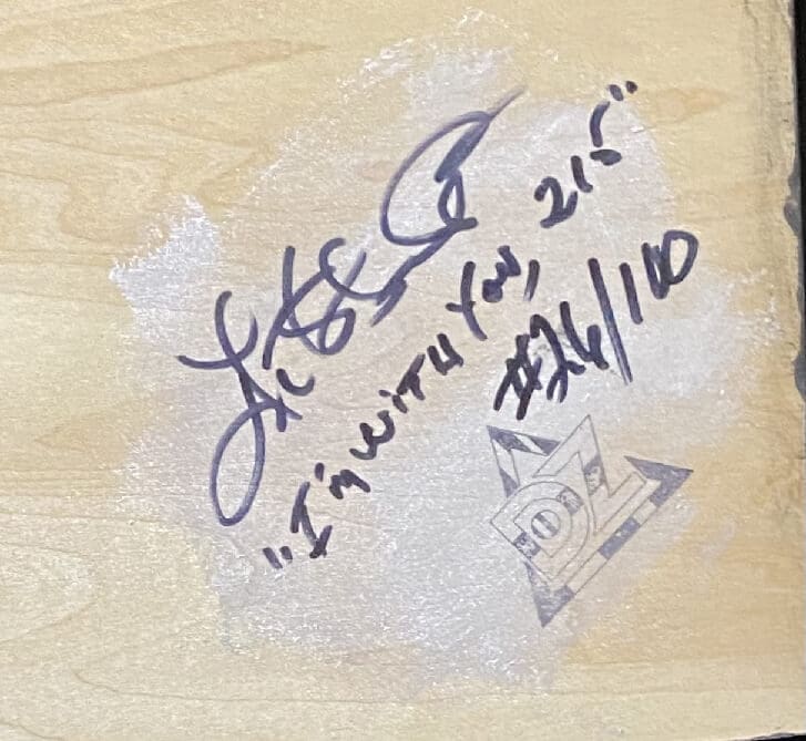 Autographed wooden surface with inscriptions and a triangle logo.
