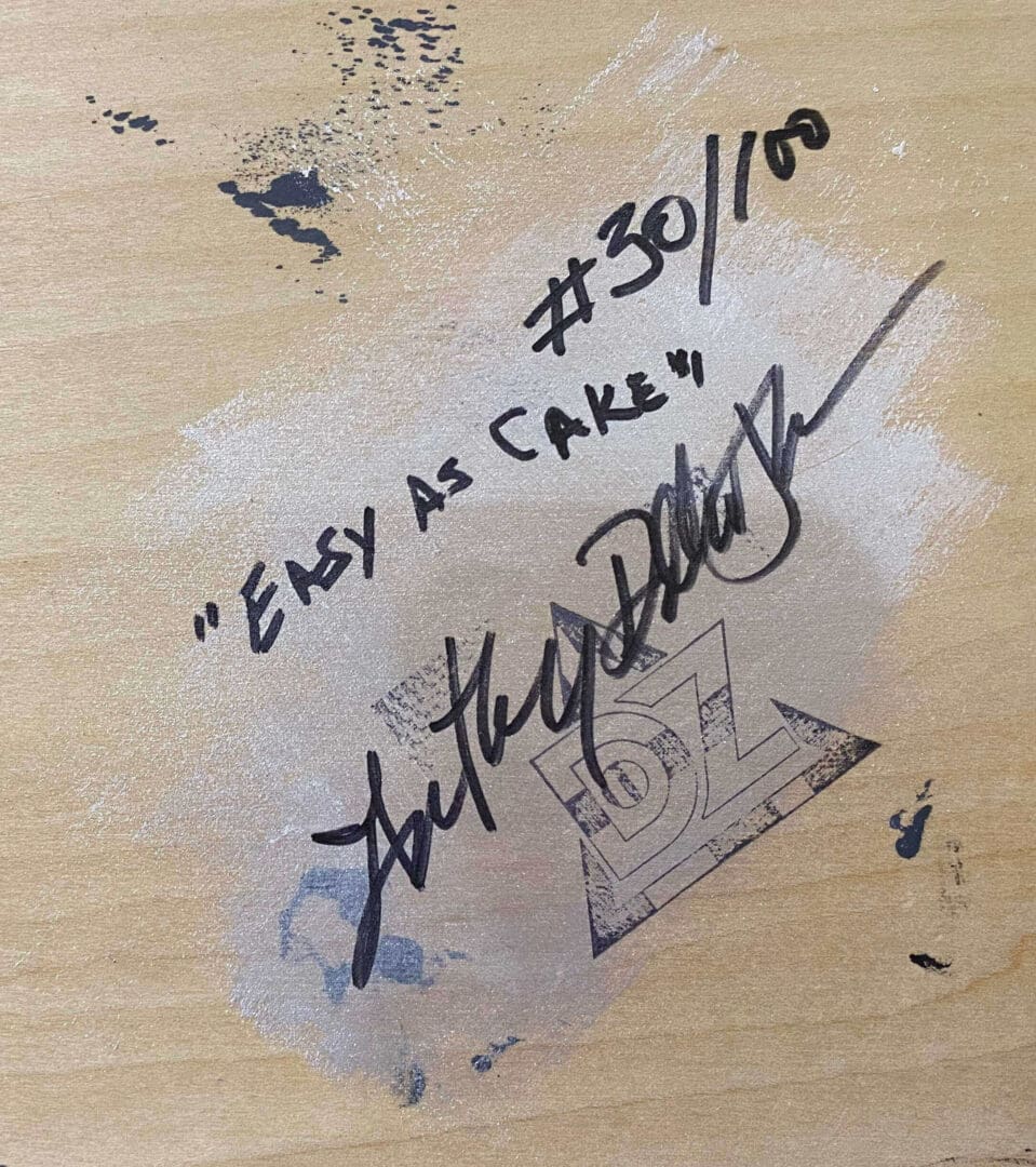 Autographed wooden surface with inscription 'Easy as Cake!' and number #30/100.