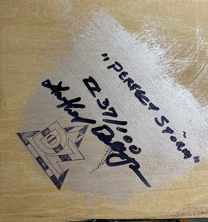 Autographed wooden surface with triangular logo.